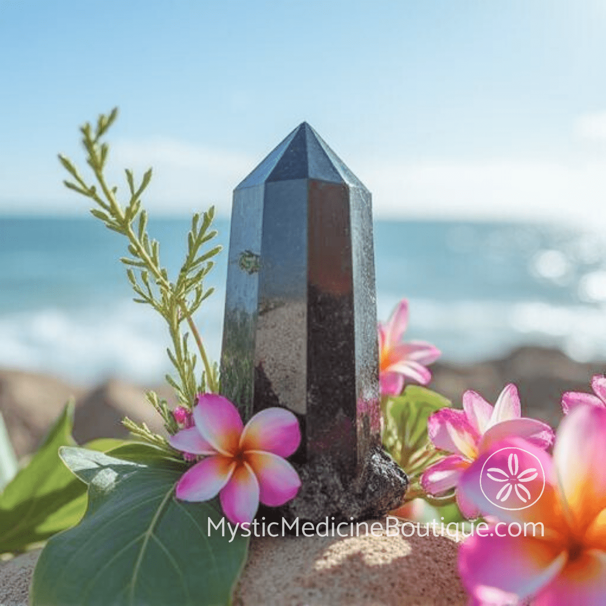 Black tourmaline crystal tower with frangipani flowers representing how black tourmaline works from integrated RN and Reiki Master perspective