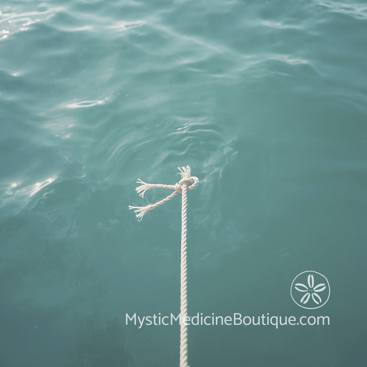 A frayed rope end floating on calm turquoise ocean water, representing psychic cord cutting and energetic release.