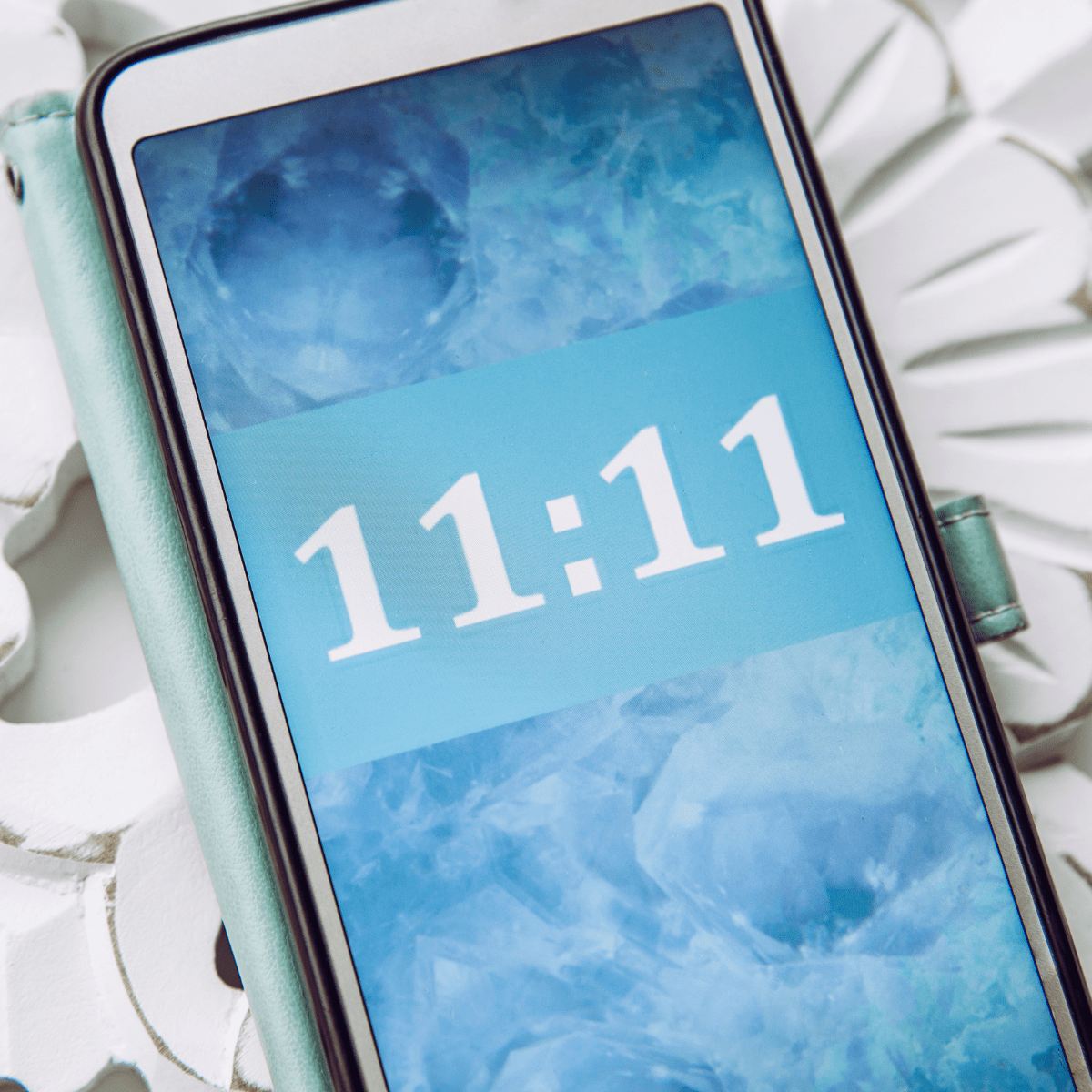 Phone displaying 11:11 angel number on blue mystical background - spiritual synchronicity and divine timing message